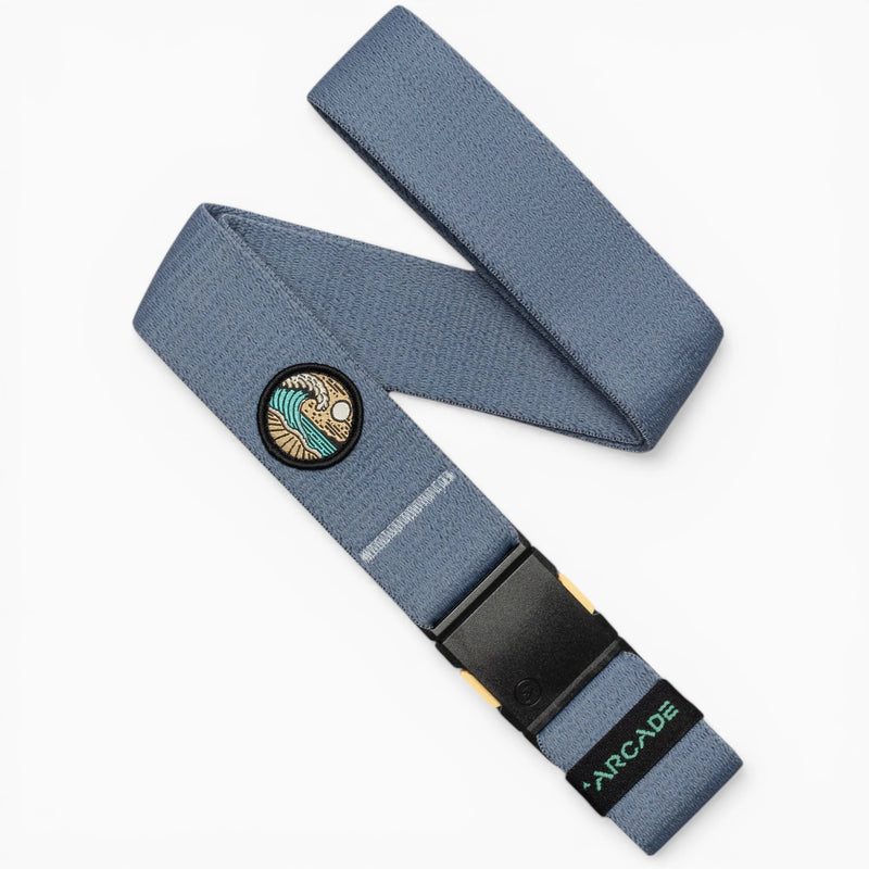The Arcade Belts Save the Waves belt in Sky features a surf-inspired patch, black buckle, and green ARCADE branding, supporting conservation efforts like Save the Waves.