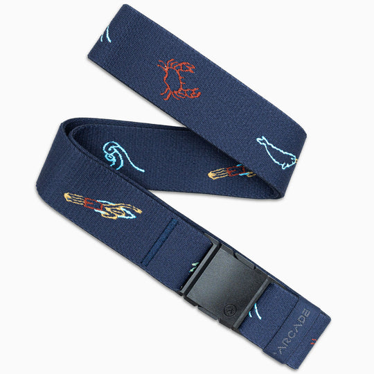 The Save the Waves elastic stretch belt by Arcade Belts features a navy blue color, embroidered sea creatures and colorful waves, a black plastic buckle, and the brand name “ARCADE” near the low-profile buckle.