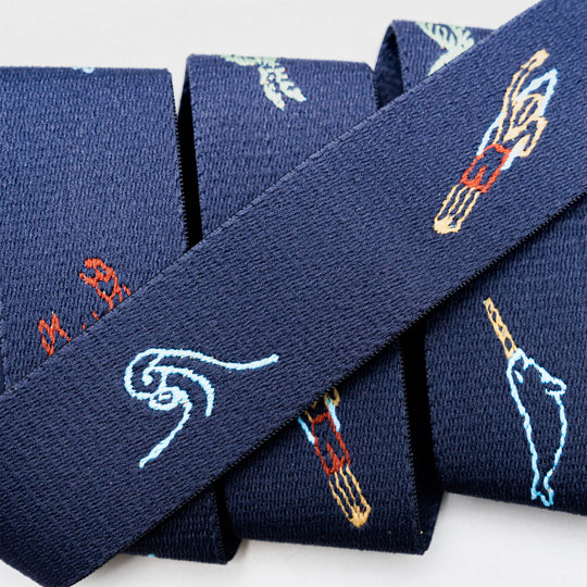 Three “Save the Waves” neckties from Arcade Belts, featuring dark blue fabric with embroidered hands holding chopsticks and stylized waves, are arranged side by side—a stylish tribute to ocean conservation.