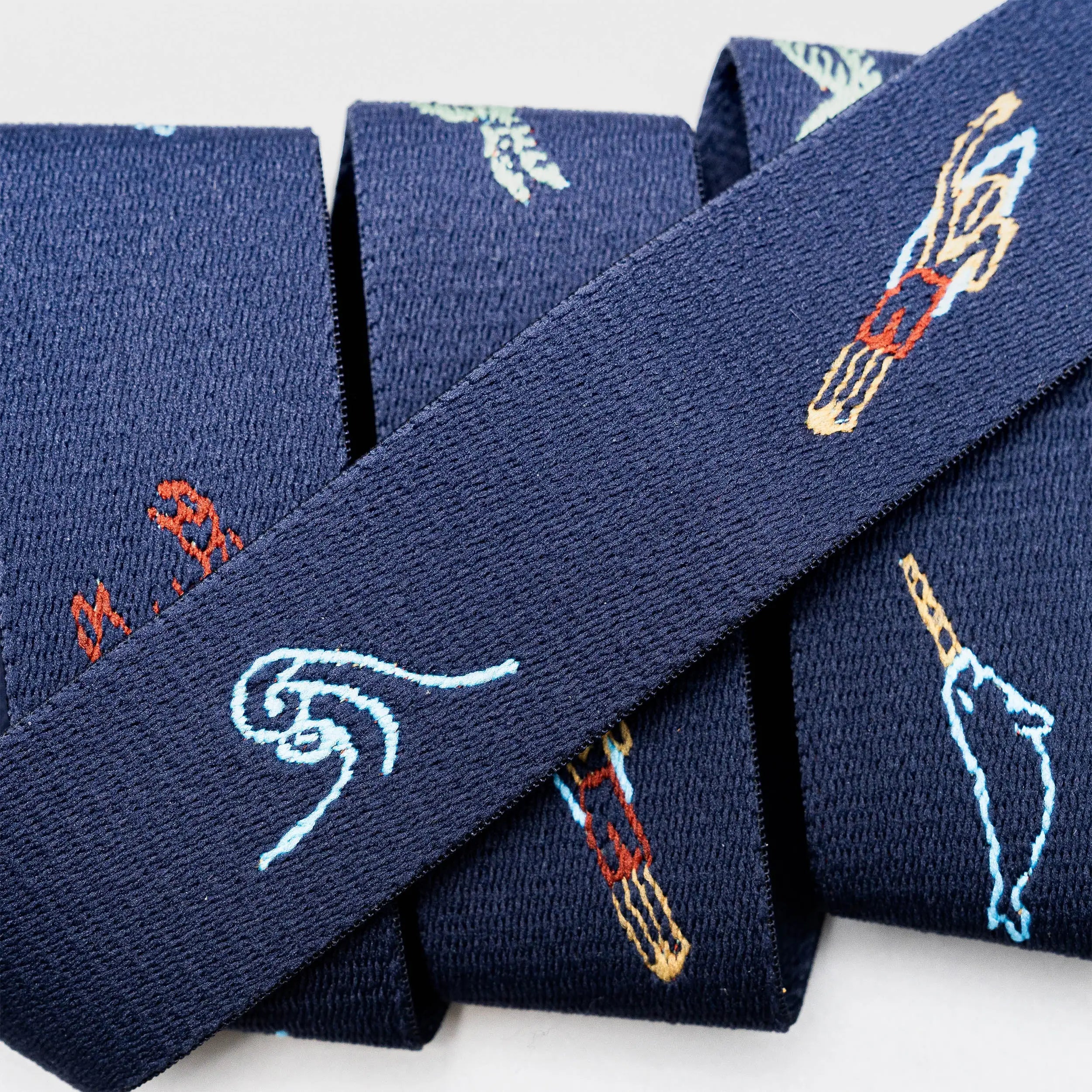Three “Save the Waves” neckties from Arcade Belts, featuring dark blue fabric with embroidered hands holding chopsticks and stylized waves, are arranged side by side—a stylish tribute to ocean conservation.