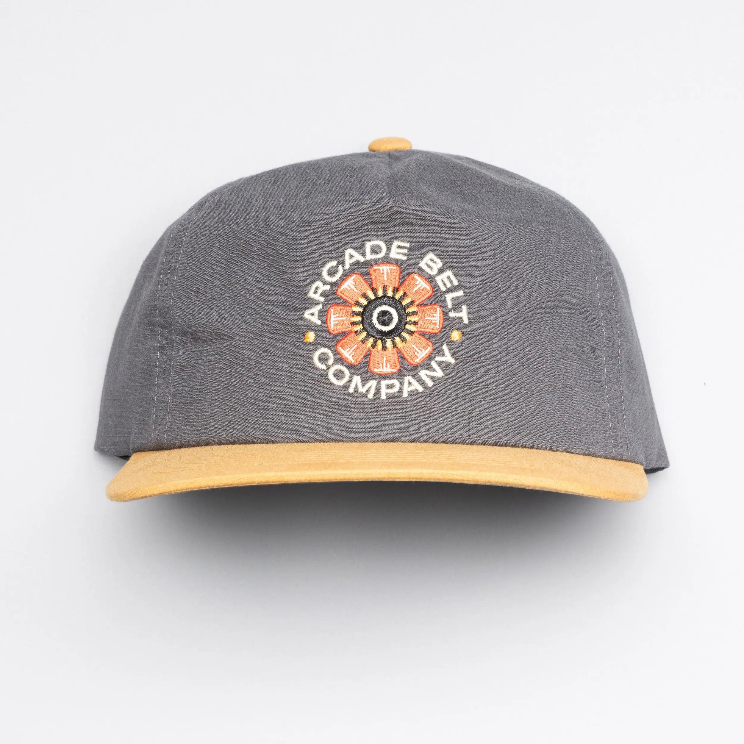 The Arcade Semi Structured Hat by Arcade Belts is a gray cap with a yellow brim and embroidered flower design, plus ARCADE BELT COMPANY on the front—ideal to pair with your favorite low profile belt.