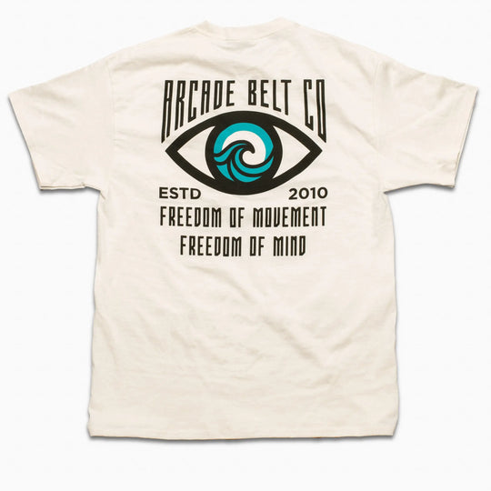 The Arcade Freedom Tee by Arcade Belts is a white T-shirt with an eye design featuring a blue wave in the iris and text: ARCADE BELT CO, ESTD 2010, FREEDOM OF MOVEMENT, FREEDOM OF MIND—celebrating adventure.