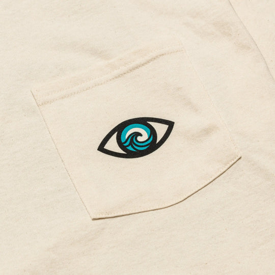 The Arcade Freedom Tee by Arcade Belts features a cream pocket with a bold black eye print, its center designed as a blue and teal ocean wave—making it the perfect playful, travel-ready match with Arcade Belts.
