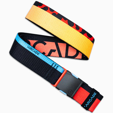 The Arcade Belts Sierra is a colorful elastic stretch belt with a black plastic buckle. One end features yellow with red and black patterns, while the other is black with blue and red accents and ARCADE visible.