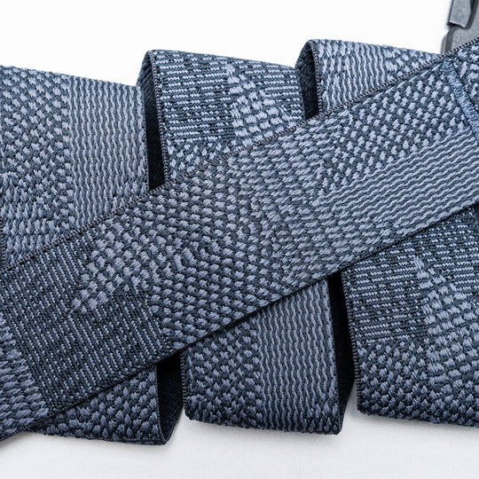 Close-up of several gray Skyline belts by Arcade Belts, featuring woven, textured webbing straps arranged in overlapping layers against a white background.