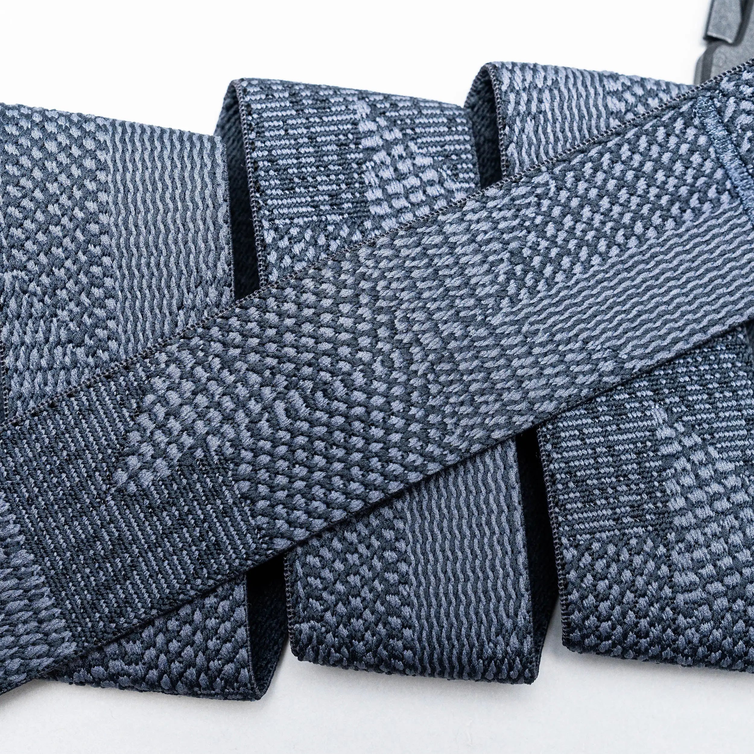 Close-up of several gray Skyline belts by Arcade Belts, featuring woven, textured webbing straps arranged in overlapping layers against a white background.