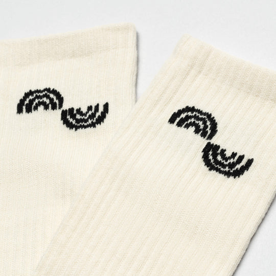Two off-white ribbed Arcade Movement Experiment Socks by Arcade Belts, featuring a black semi-circular wave pattern near the top, are laid flat on a light background—versatile enough for any adventure.