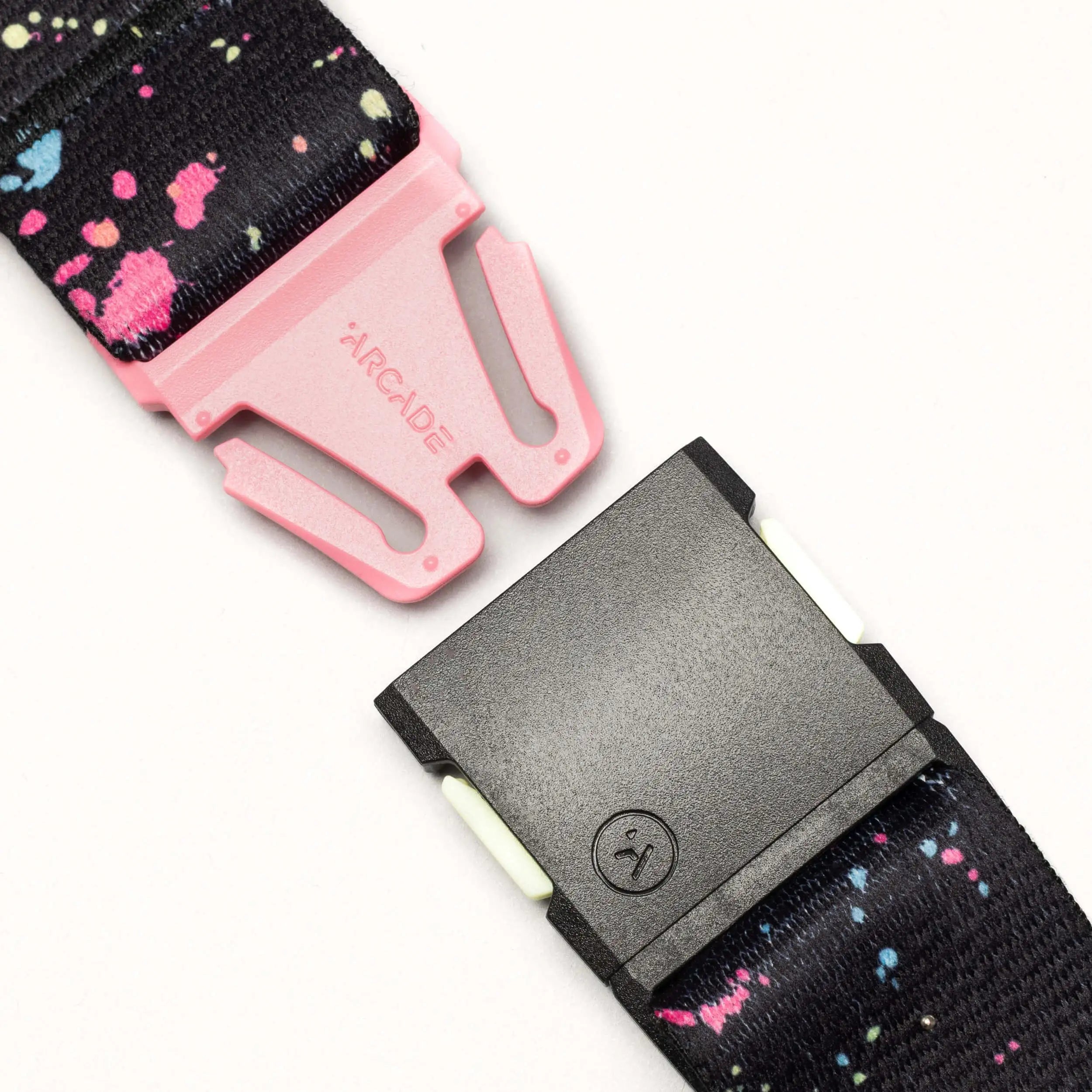 A close-up of the Arcade Belts Splatter: a black belt with vibrant pink and blue drip splatters, a pink ARCADE-labeled buckle, and a black clasp, shown against a light background.