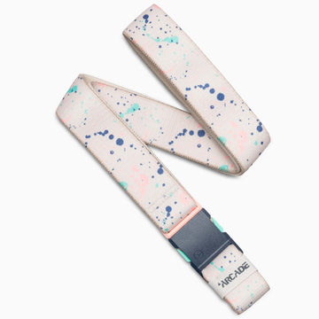 The Arcade Belts Splatter is a beige fabric belt with blue, green, and pink paint splatters, a dark gray buckle, and a small ARCADE logo near the end. It is displayed on a white background.