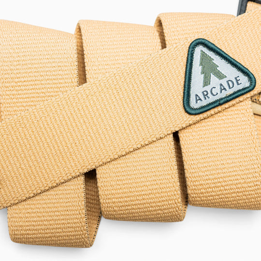 A beige woven belt from Arcade Belts features a green and white triangle patch with a pine tree and the word “Treeple,” making it perfect for representing your love for the Treeple community or enjoying time outdoors among the trees.