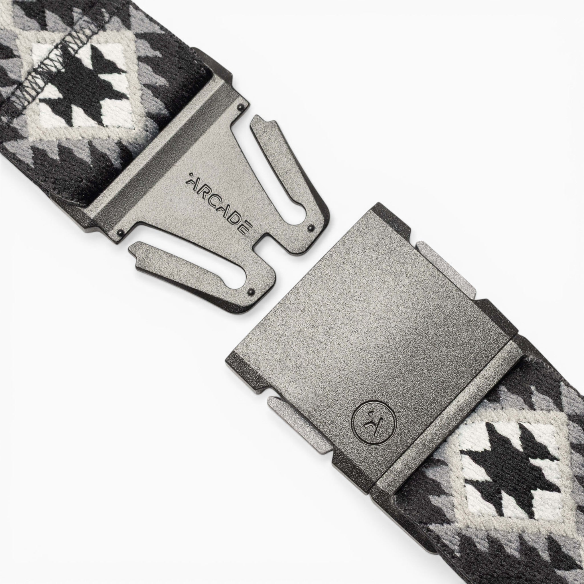 A close-up of the Arcade Belts Vernan Kee belt, featuring a geometric black and white pattern inspired by Navajo rug designs and a metal buckle labeled “ARCADE,” shown partially unclasped on a white background.
