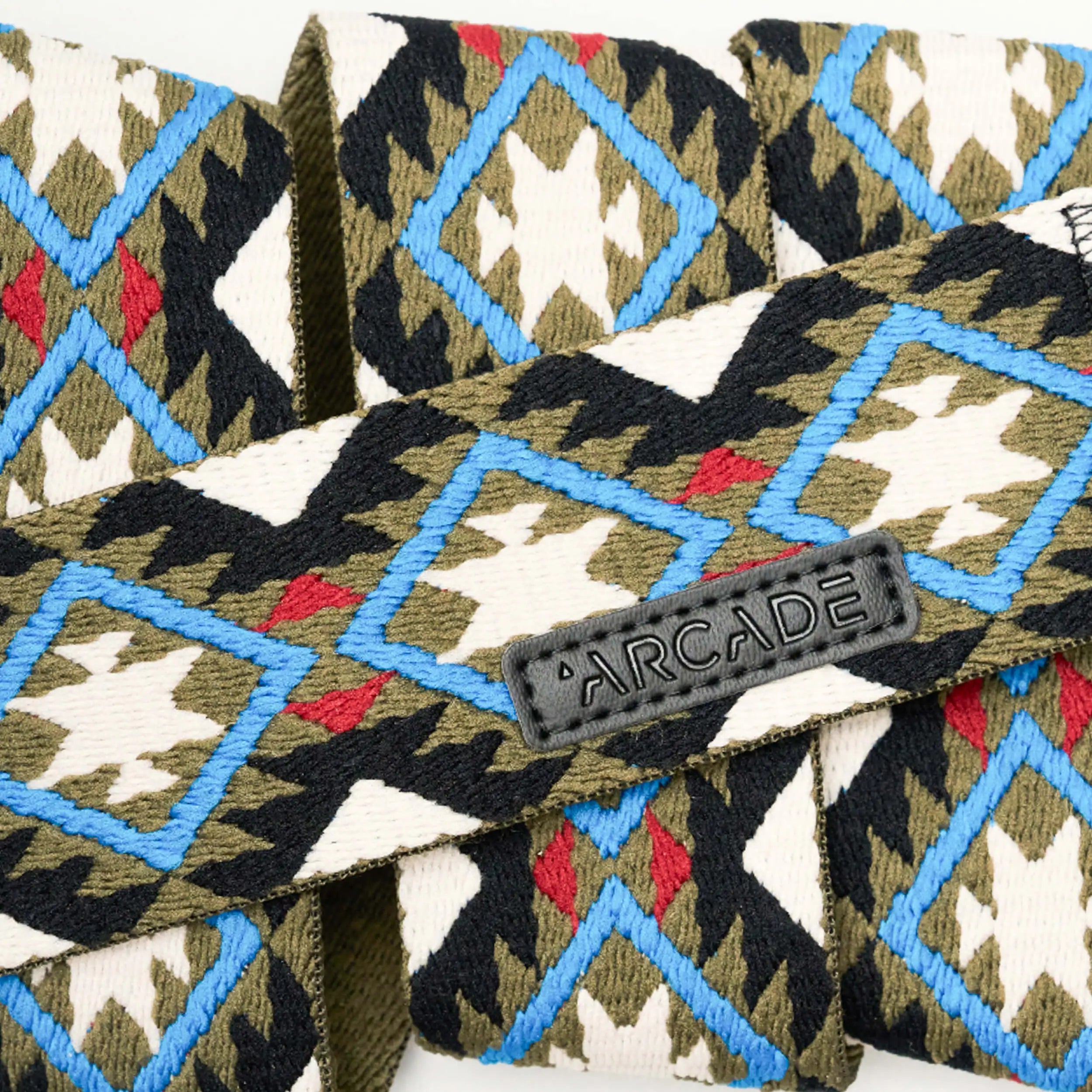 The Vernan Kee by Arcade Belts is a woven elastic stretch belt with a blue, red, olive green, black, and white geometric pattern, featuring a plastic buckle and black ARCADE tag—ideal for stylish travel belt enthusiasts.