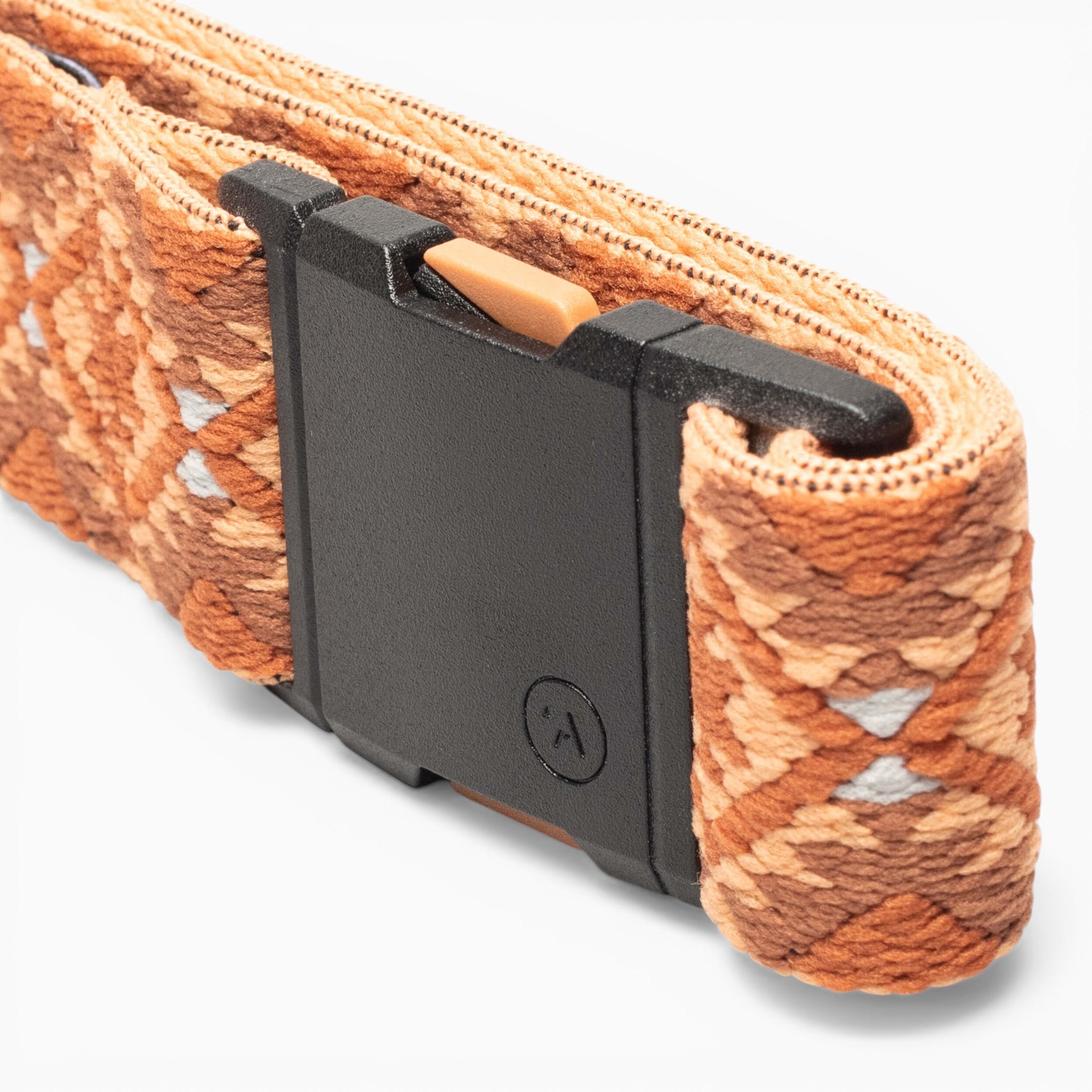 A close-up of the Arcade Belts Vernan Kee strap showcases a woven brown geometric pattern with light blue accents, reminiscent of traditional rug motifs and Navajo-inspired shapes. The strap features a black plastic buckle adorned with a small circular logo.