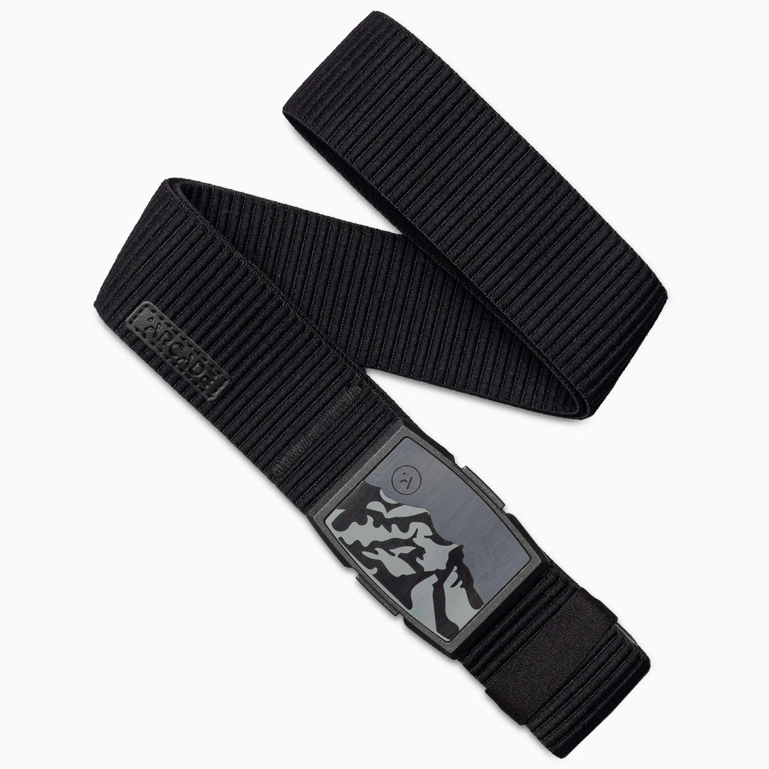 The Arcade Belts Woody Kit is a black elastic stretch armband with a rectangular buckle featuring a mountain design, highlighting the brand’s signature craftsmanship and travel-ready style.